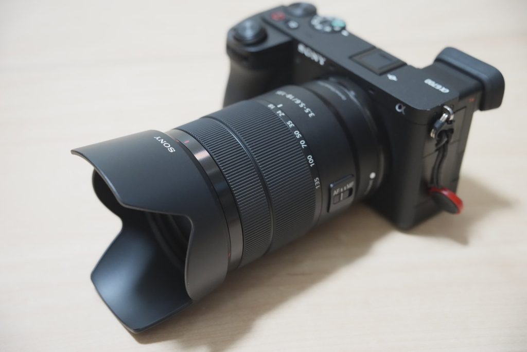 ズームレンズとレンズフードを装着したSONY α6700を前方左側から撮影した様子